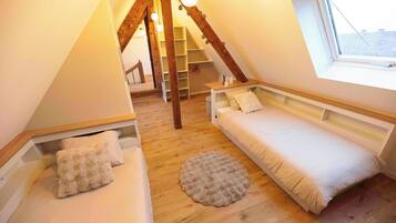 Una camera da letto mansardata accogliente con due letti, una scala in legno e un lucernario.
