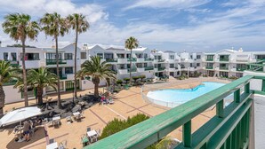 Ein Resort mit mehreren weißen Gebäuden, einem Swimmingpool, Palmen und Sitzbereichen im Freien.