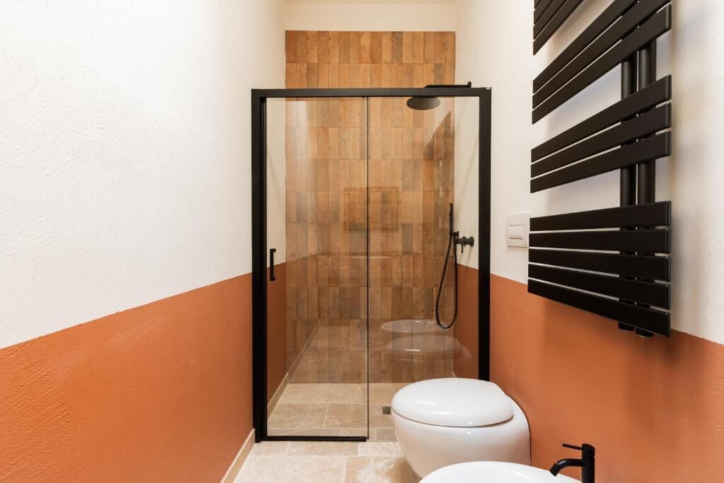 Un baño con cabina de ducha de vidrio, inodoro y lavamanos.