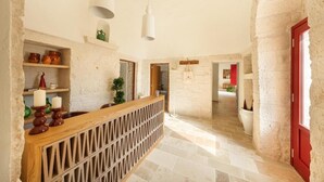 A hallway with stone walls, a wooden reception desk, and a red door. - Trulli D Amore (Monopoli)