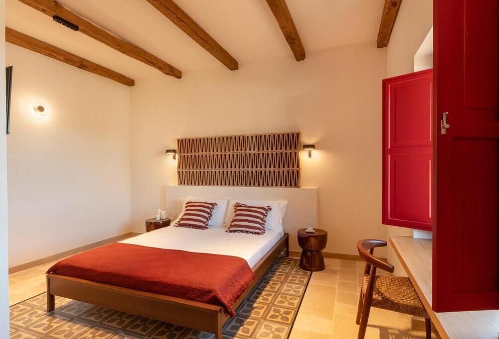 Um quarto com uma cama de madeira, um guarda-roupa vermelho e um chão estampado.
