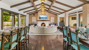 A spacious living area with a fireplace, wooden beams, and a dining setup with chairs and a table. - 20 beds,2 pkleball+bball, 5 acre estate gameroom (Bermuda Dunes)