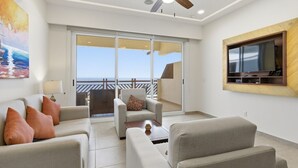 Ein modernes Wohnzimmer mit einer Sofagarnitur, einem Couchtisch und einem an der Wand befestigten Fernseher.