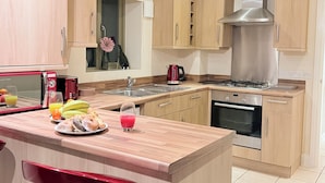 Eine moderne Küche mit Holzschränken, einer Edelstahl-Dunstabzugshaube, einem Einbauofen, einem Spülbecken und einer Arbeitsplatte mit Frühstücksgebäck.