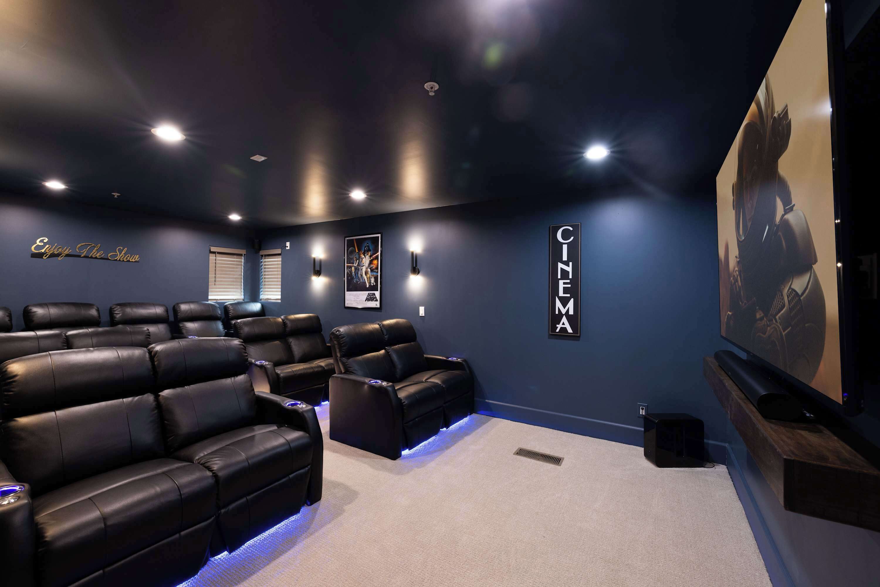 A home theater with black leather reclining seats, a large screen, and a wall-mounted projector.