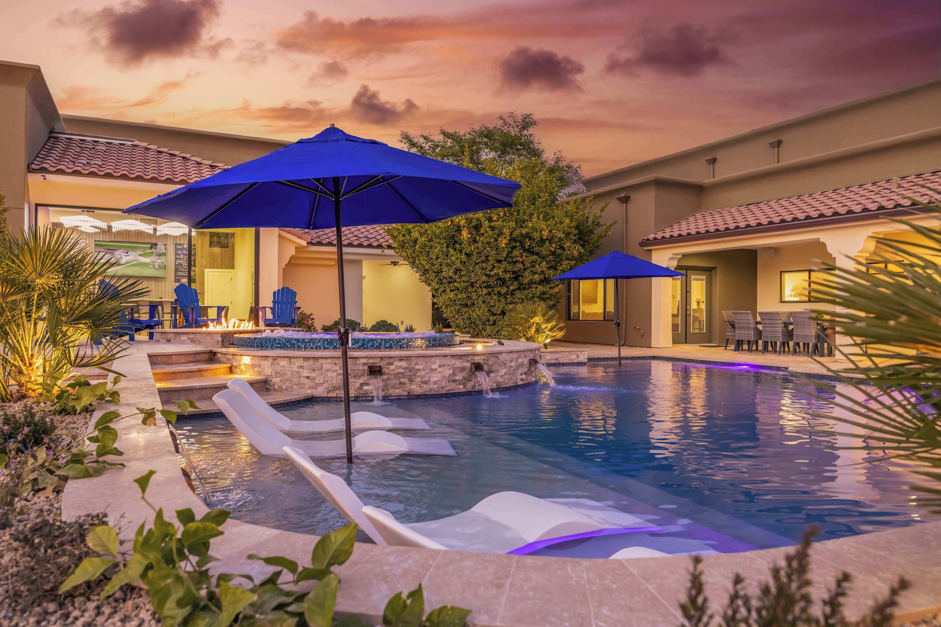 A swimming pool with lounge chairs and umbrellas, surrounded by a landscaped garden.
