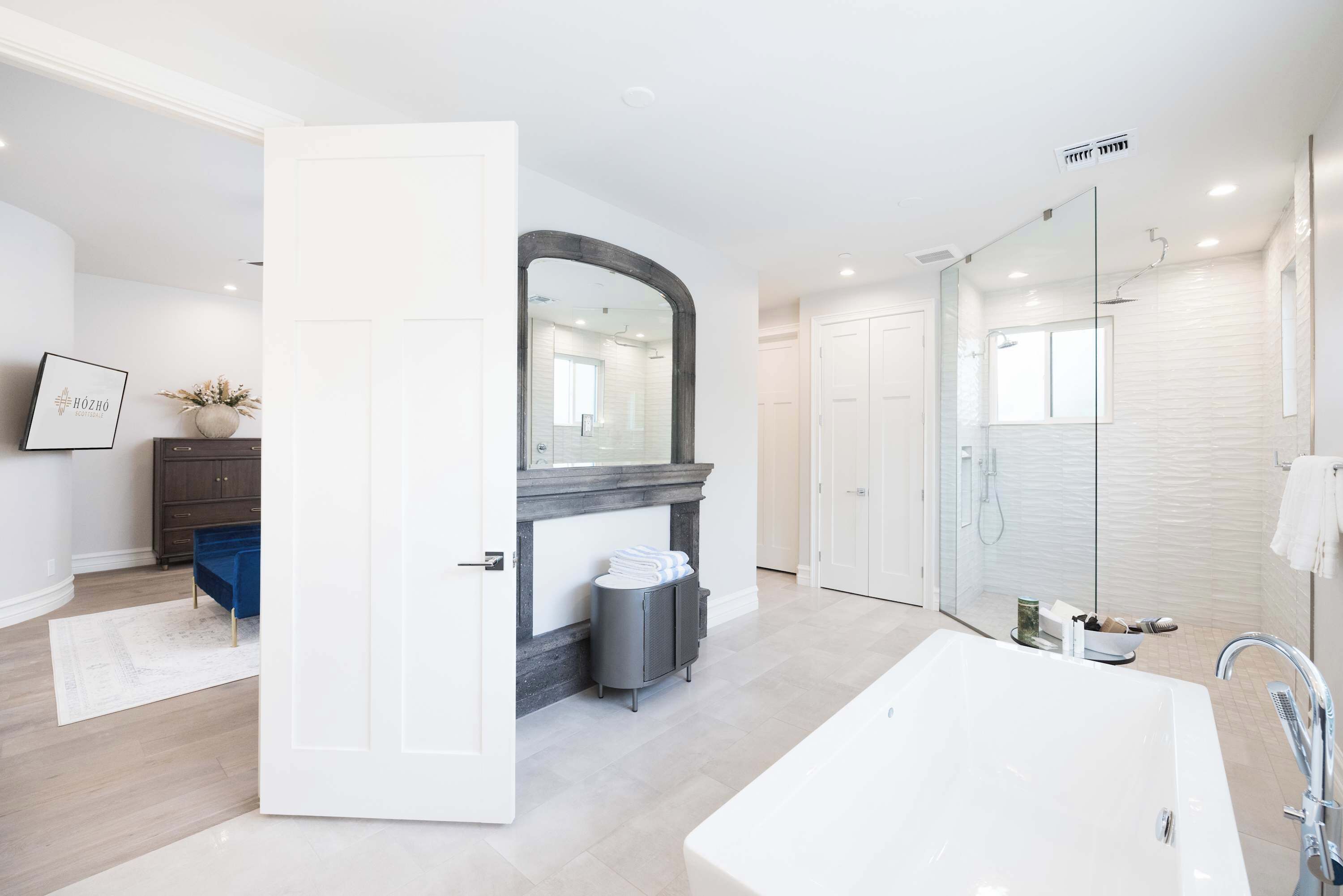 A modern bathroom with a large bathtub, a shower area, and a vanity with a mirror.