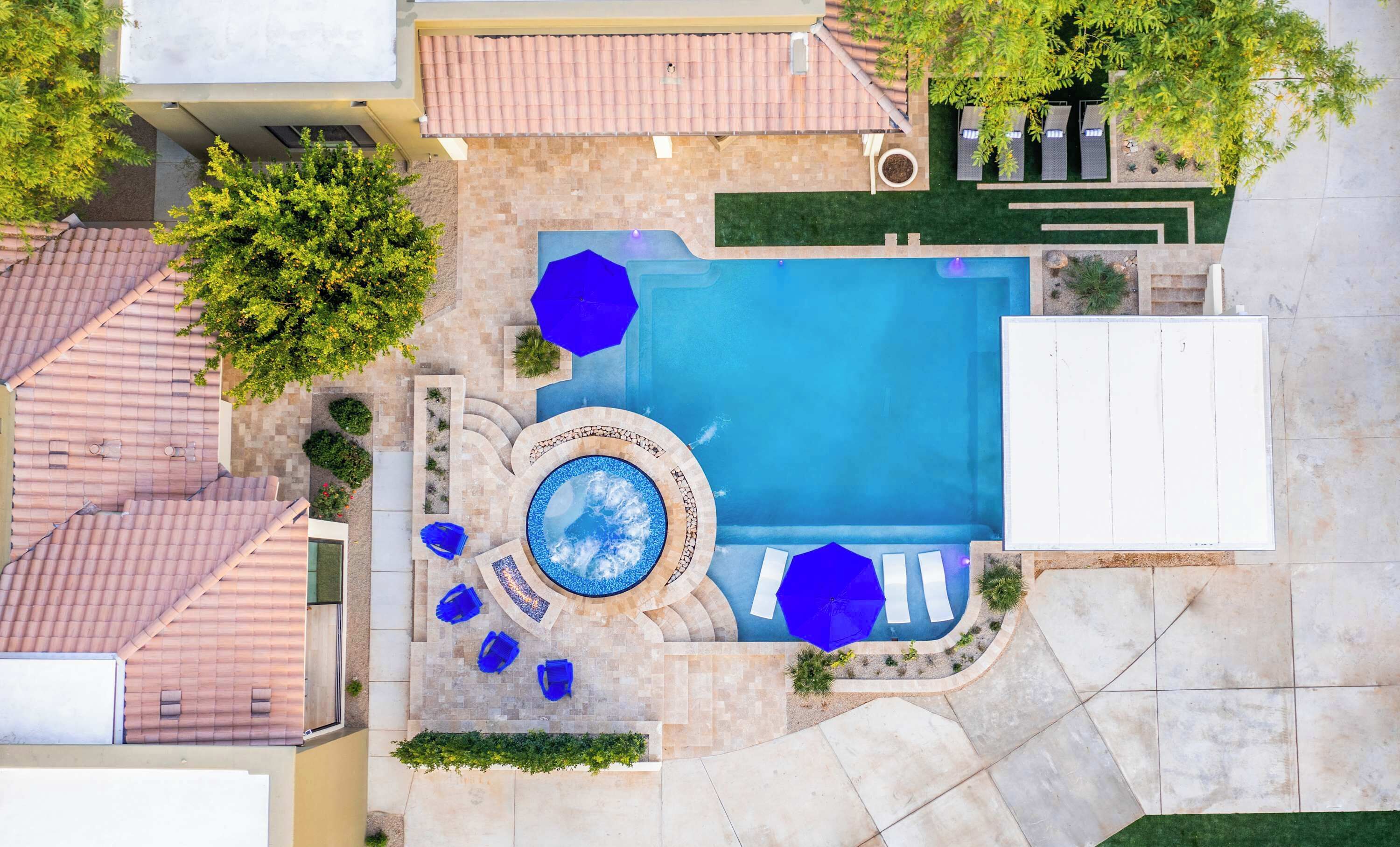 Vista aérea de un patio trasero residencial con piscina, jacuzzi y mobiliario exterior.