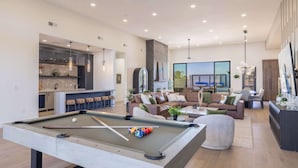 A modern living room with a pool table, a sofa set, and a dining area. - HÓZHÓ | Pool, Hot Tub, Theatre, Sauna & Fire Pit (Scottsdale)