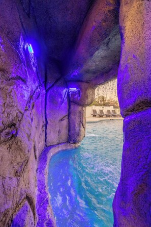 Un área de piscina con formaciones rocosas y sillones de descanso.