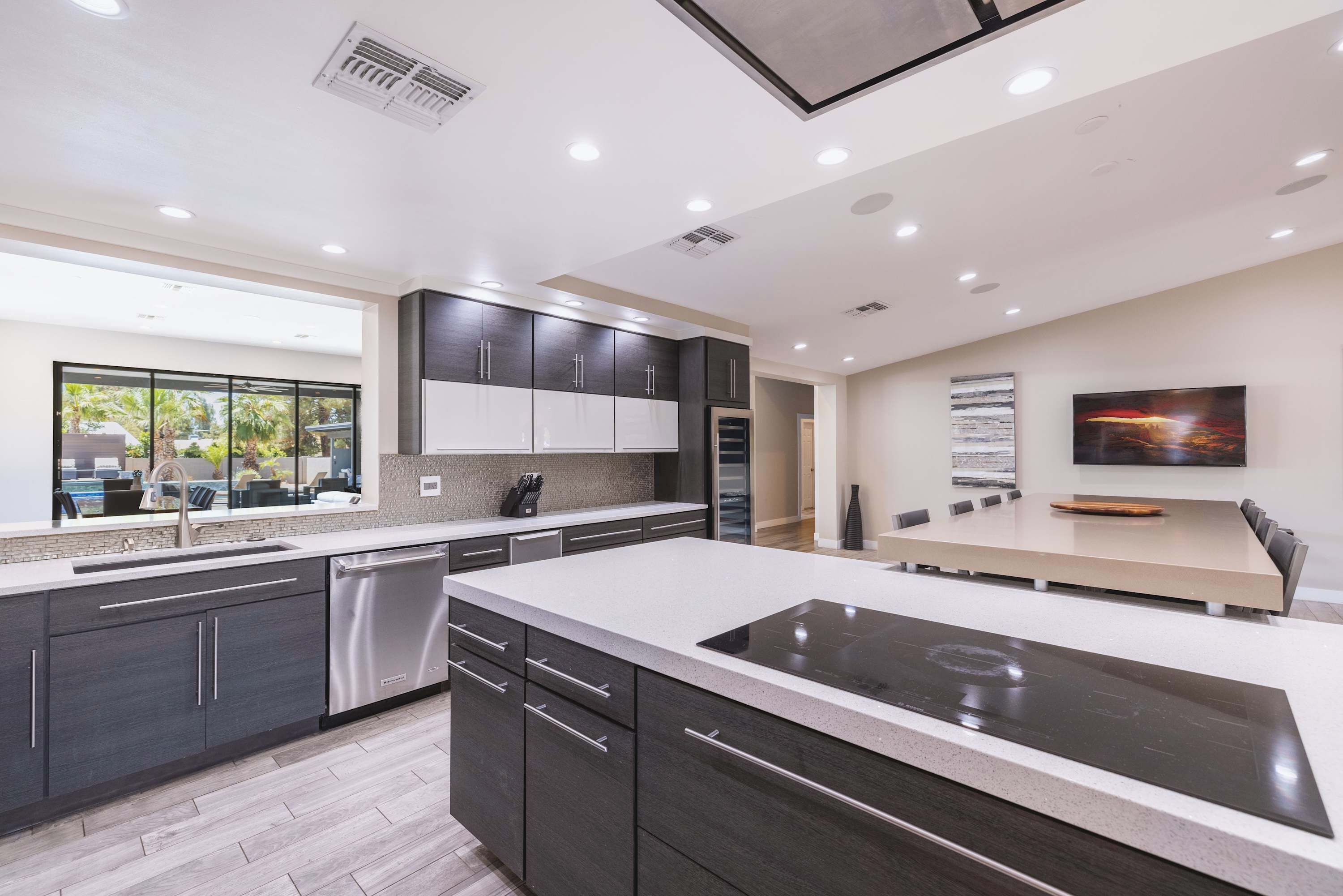 A modern kitchen with a large island, built-in appliances, and a dining area with a long table.