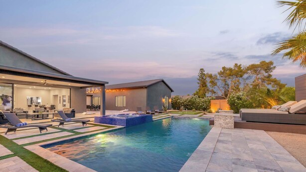 Une maison moderne dotée d’une piscine, d’un espace salon extérieur et d’une pelouse bien entretenue.