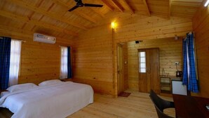 A wooden cabin with a bed, a table, and a kitchenette.