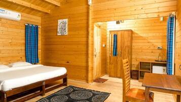 A wooden cabin with a bed, a table, and a chair.