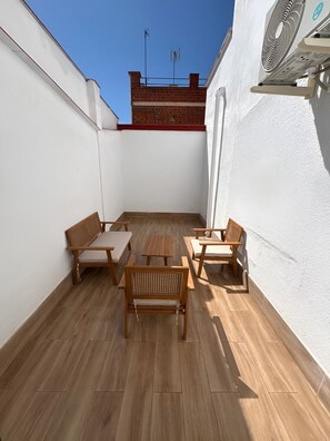 A rooftop patio with wooden furniture and a fan. - Collection Las Ventas Apartamento C cerca de la Plaza de Toros (Madrid)