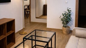 A modern living room with a glass coffee table, a sofa, a floor lamp, and a mirror. - Collection Las Ventas Apartment 1D near the Bullring (Madrid)