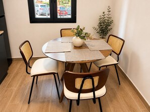 Une table de salle à manger ronde, entourée de six chaises, un vase rempli de fleurs et une plante en pot.