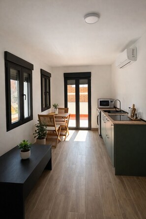 A modern kitchen with a built-in microwave, a wooden dining table with chairs, and a bench. - Collection Las Ventas Apartamento E cerca de la Plaza de Toros (Madrid)