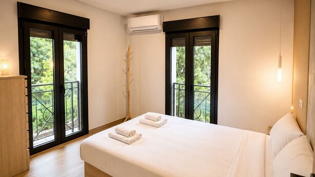 A bedroom with a bed, two windows with black frames, an air conditioning unit, and a wooden floor. - Collection Las Ventas Apartamento G cerca de la Plaza de Toros (Madrid)