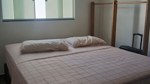 Ein Schlafzimmer mit einem Bett, einem Fenster und einem hölzernen Kopfseitenverkleidung.