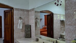 A bathroom with a large mirror, two towels hanging on towel rings, a sink, and a toilet.