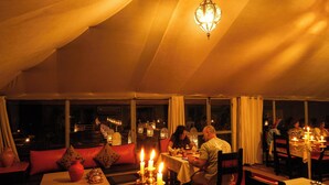 An indoor dining area with tables, chairs, and a hanging light fixture. - Merzouga Desert Camp (Merzouga)