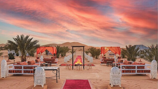 A desert wedding setup with a red carpet, white lanterns, and a fire in the center. - Merzouga Desert Camp (Merzouga)