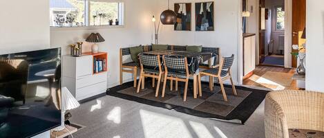 A modern living room with a dining area, a TV, and a bookshelf.