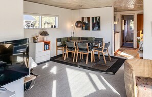 Ein modernes Wohnzimmer mit Essbereich, Fernseher und Bücherregal.