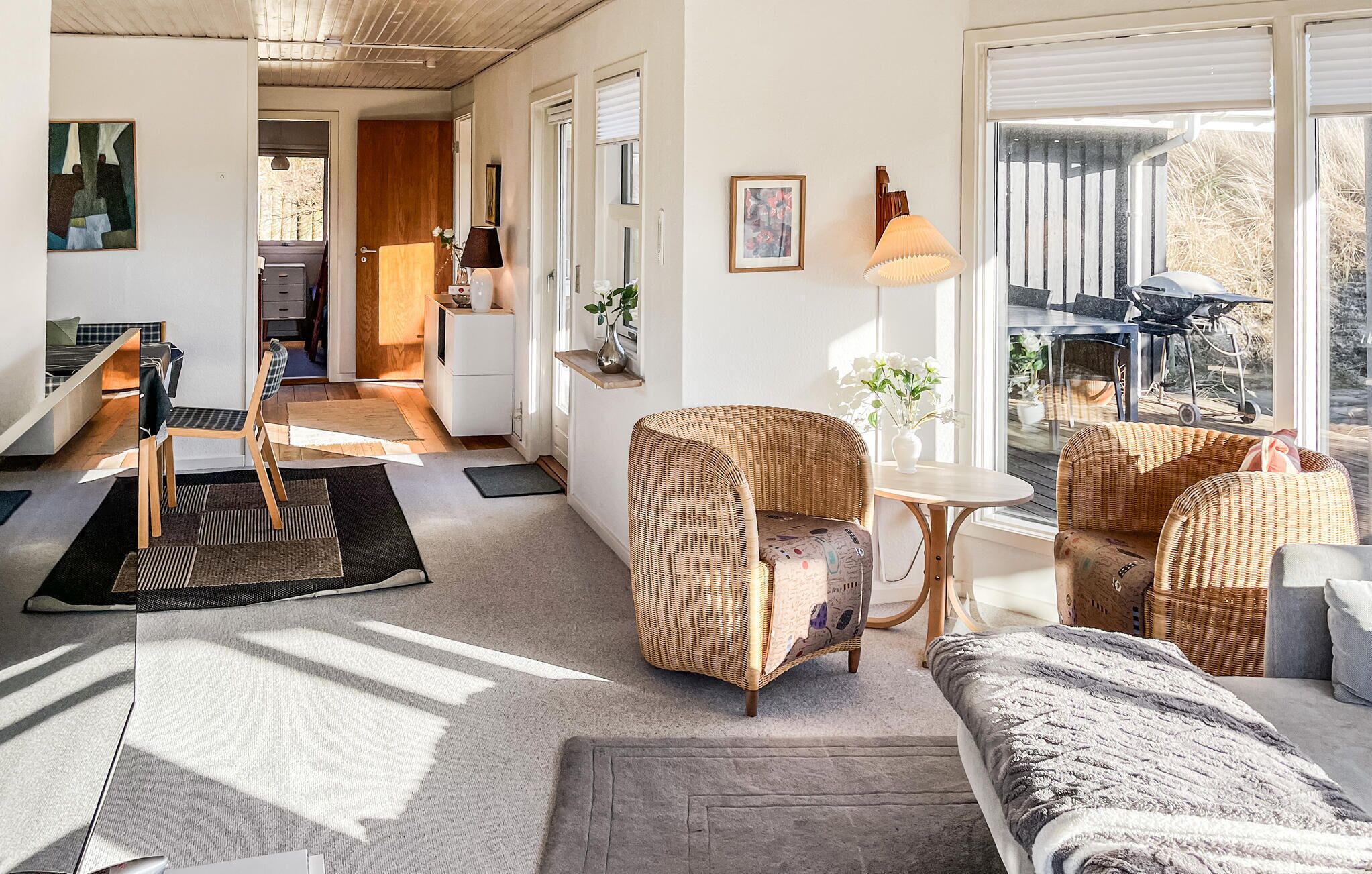 Una sala de estar moderna con muebles de mimbre, una mesita y vistas al exterior.