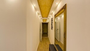 Un couloir étroit doté d’un plancher en bois, d’un éclairage encastré et d’un grand miroir sur le mur de droite.