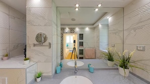 Une salle de bain moderne avec un grand miroir, un lavabo rond et des plantes en pot.