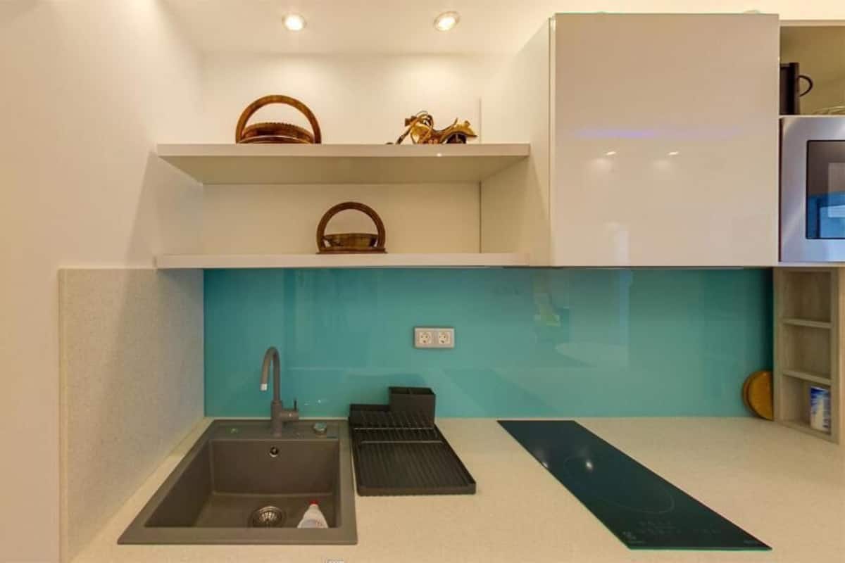 A compact kitchen with a sink, a countertop, and a backsplash.
