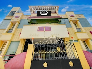 A hotel with a prominent sign, a gated entrance, and a multi-story structure. - Deluxe Guna Residency (Tirupporur)