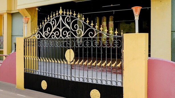 A gated entrance with ornate metalwork and circular decorative elements. - Deluxe Guna Residency (Tirupporur)