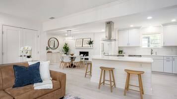 A modern kitchen with white cabinetry, a central island, and bar stools.
