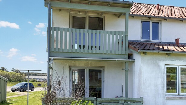Un edificio a due piani con un balcone, un posto auto coperto e un garage.