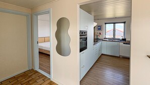 Una cucina compatta con mobili bianchi, forno integrato e una finestra con vista.