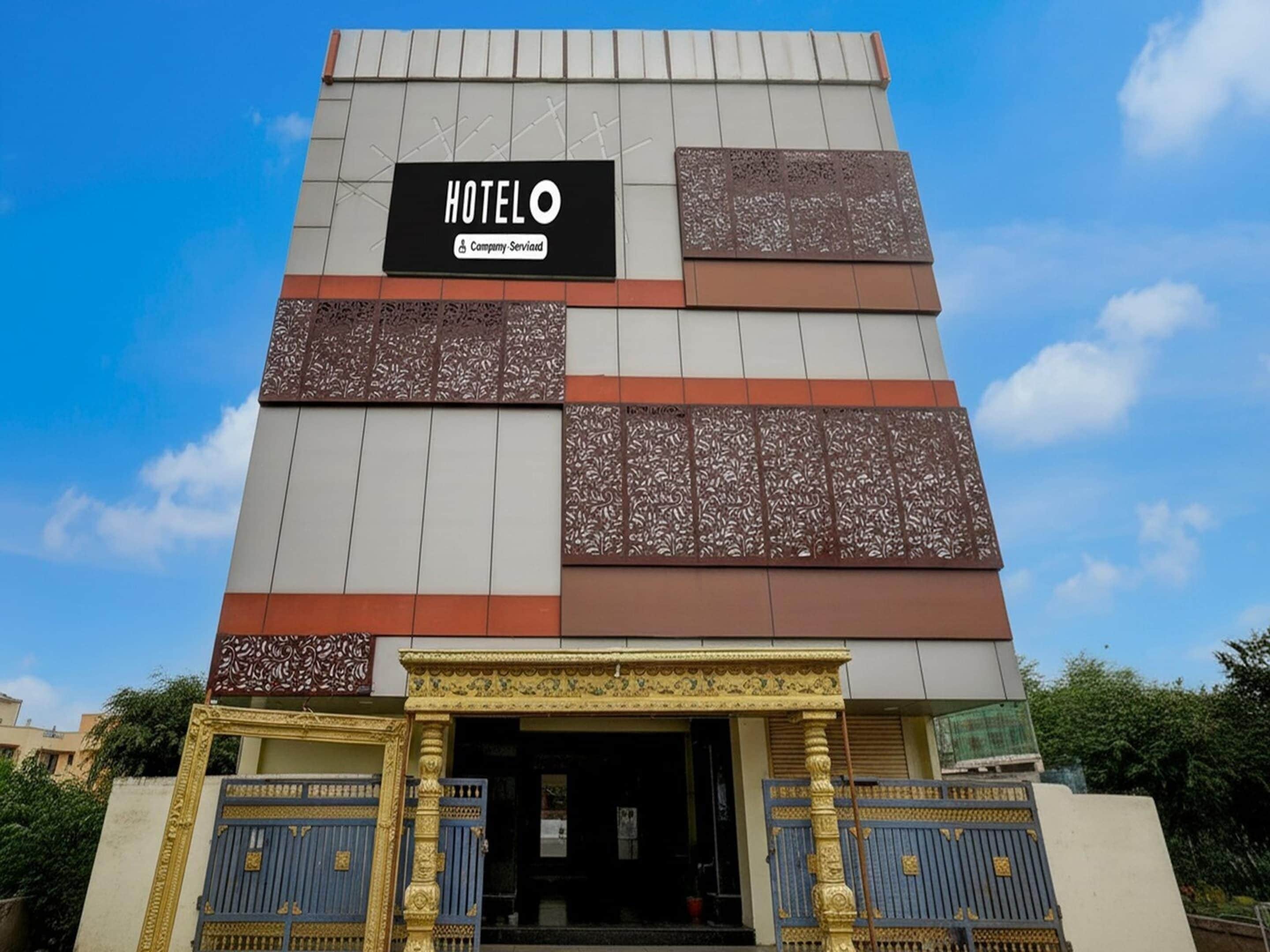 A hotel with a sign reading 'HOTELO' and 'Company Serviard.' It features a modern facade with decorative panels and a traditional entrance with ornate gates.