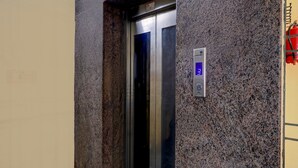 Un ascensor con una pantalla digital que muestra el número 3, un extintor montado en la pared y una pared con textura.