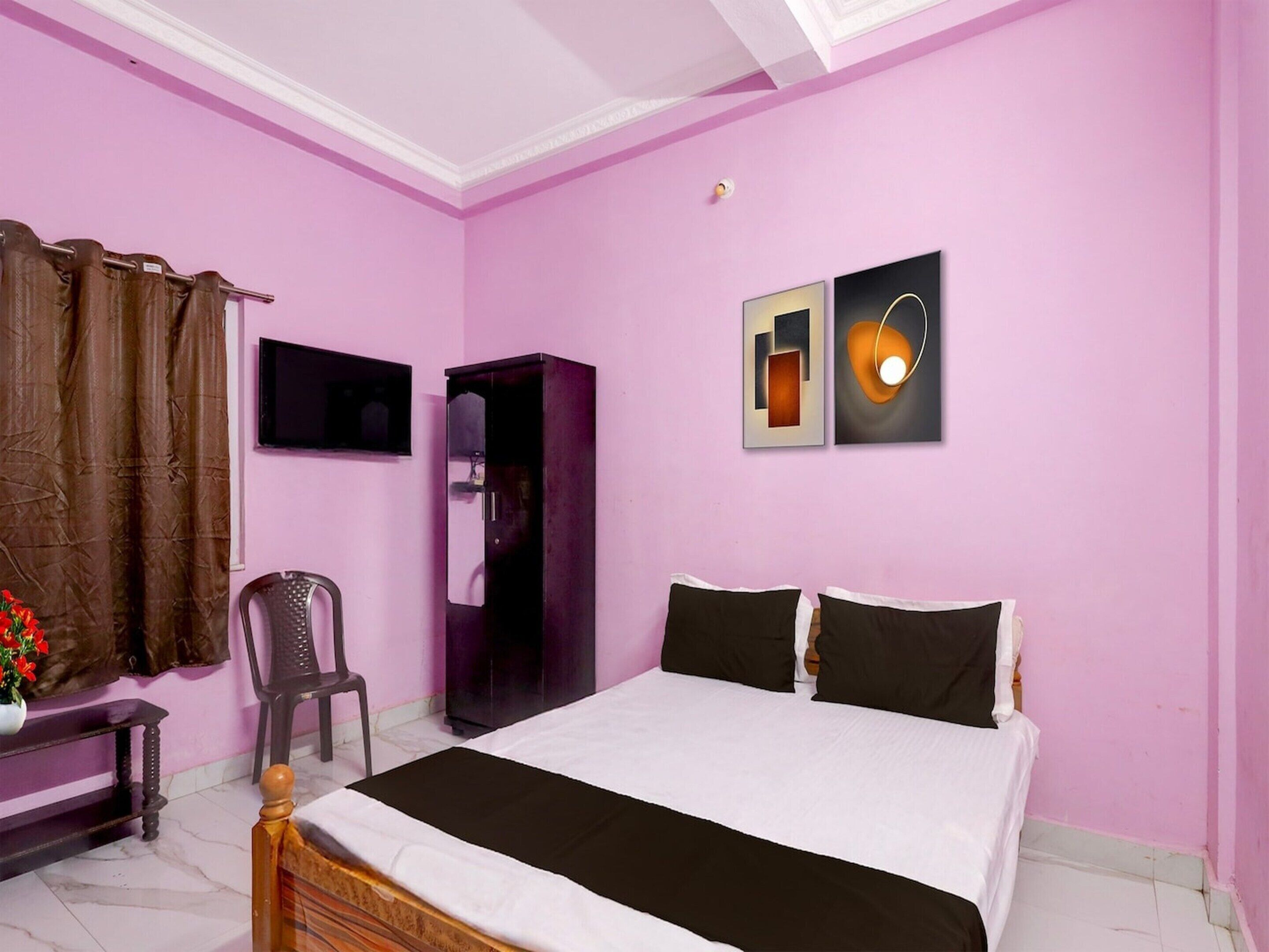 A bedroom with a bed, a chair, a wardrobe, and a television.