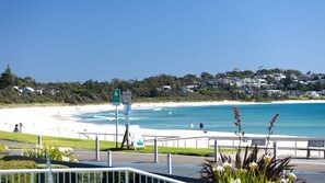 A coastal beach with a clear view of the ocean, a sandy shore, and a residential area in the background. - Ocean Hollow Retreat - Your next Mollymook getaway! (Mollymook)