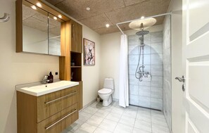 A modern bathroom with a wooden vanity, a toilet, a shower with a glass door, and a large mirror. - Nice home in Lemvig with WiFi (Lemvig)