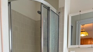 Ein Badezimmer mit einer gläsernen Duschkabine, einem Waschbecken mit Spiegel darüber und einer Toilette.