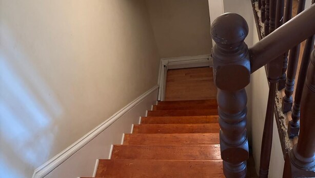 Eine Holztreppe mit Handlauf und einer Lampe darüber.