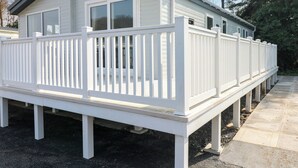 Un camper bianco con veranda coperta e terrazza recintata.