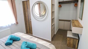 Una camera da letto con un letto, uno specchio rotondo, un armadio e un piccolo sgabello.