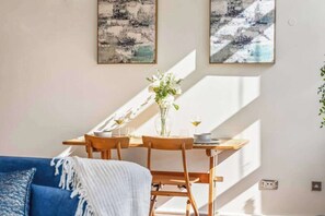 A dining area with a table, chairs, a vase with flowers, and two abstract paintings on the wall. - Stylish Jewellery Quarter Loft | Terrace and free parking (Birmingham)