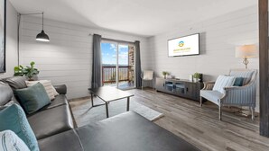 Een moderne woonkamer met een bank, salontafel, televisie en uitzicht op de omgeving.