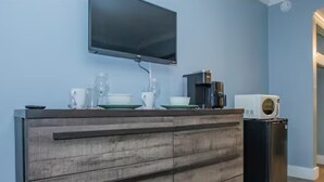 A kitchen with a flat-screen TV mounted on the wall, a coffee maker, and a microwave on the counter.